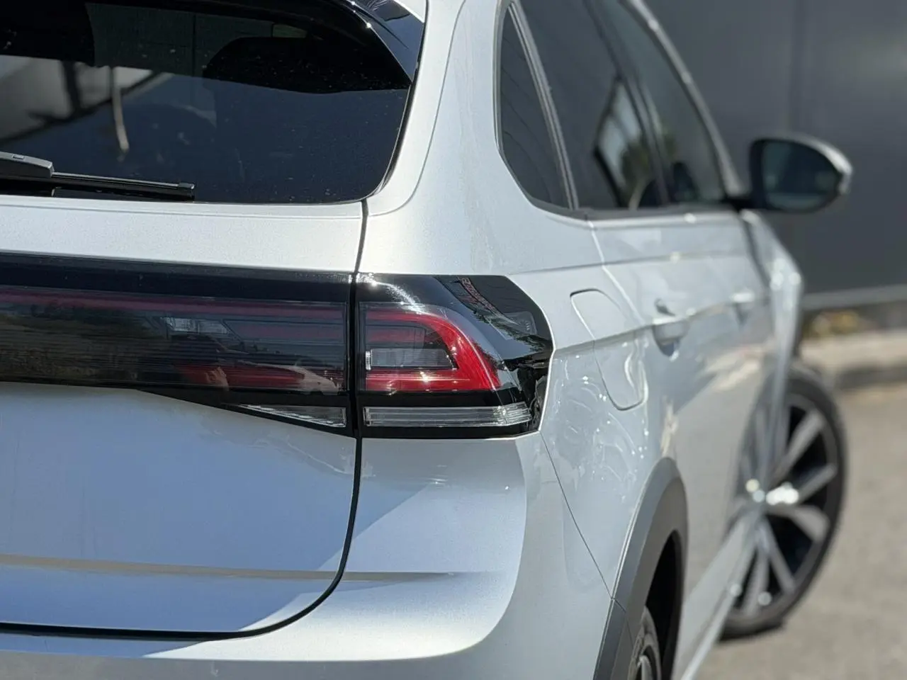 Vue 3/4 arrière droite du Volkswagen Taigo TSI 116 DSG R-Line argent Reflex, avec feux arrière LED et jantes alliage 18 pouces.