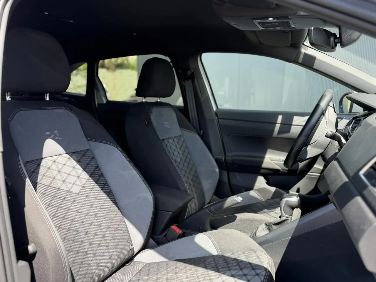 Vue intérieure côté gauche du Volkswagen Taigo TSI 116 DSG R-Line 2025, sièges sport en tissu R-Line gris et noir.