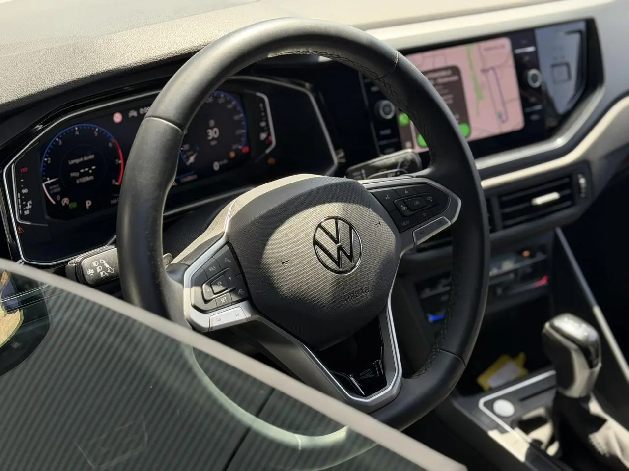 Vue intérieure centrée sur le volant cuir multifonctions et le tableau de bord numérique du Volkswagen Taigo TSI 116 DSG R-Line.