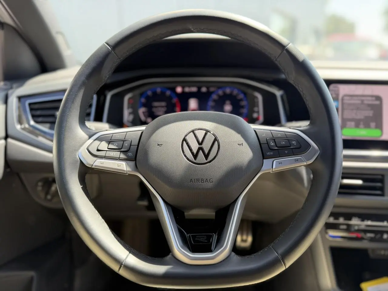 Vue rapprochée du volant cuir multifonctions Volkswagen Taigo R-Line avec logo central et commandes intégrées.
