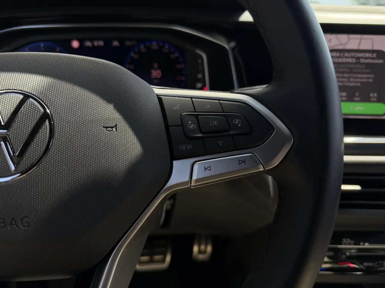 Gros plan sur le volant multifonctions en cuir du Volkswagen Taigo TSI 116 DSG R-Line, avec commandes intégrées.