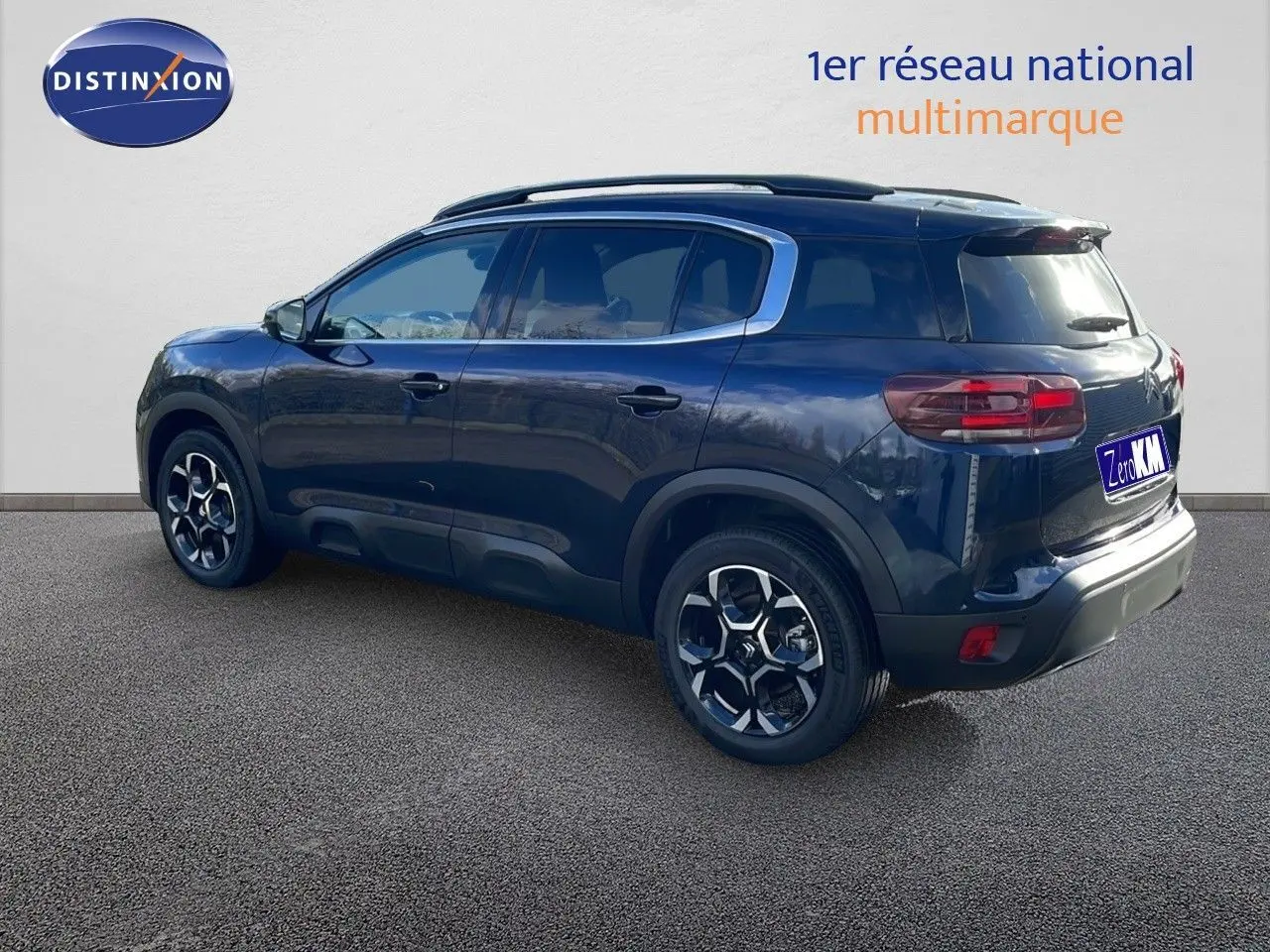 Vue 3/4 arrière droite d'un Citroën C5 Aircross bleu Eclipse Metal avec jantes alliage et barres de toit.