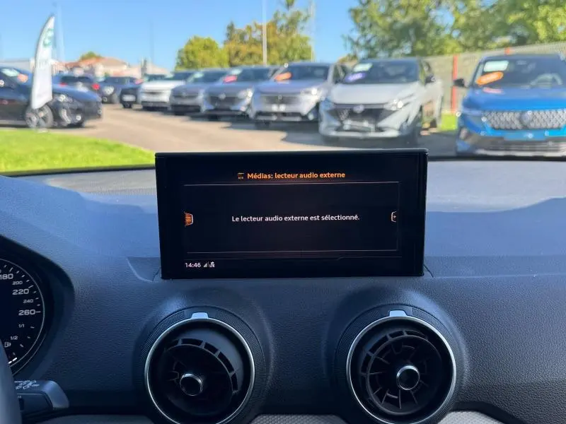 Vue intérieure du tableau de bord de l'Audi Q2 35 TFSI S line 2023 avec écran central affichant un lecteur audio externe.