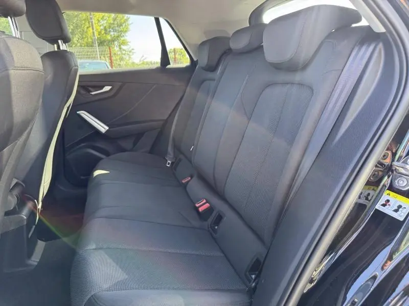 Vue intérieure côté droit des sièges arrière noirs du SUV Audi Q2 35 TFSI S line 2023 avec ceintures et appuie-têtes.