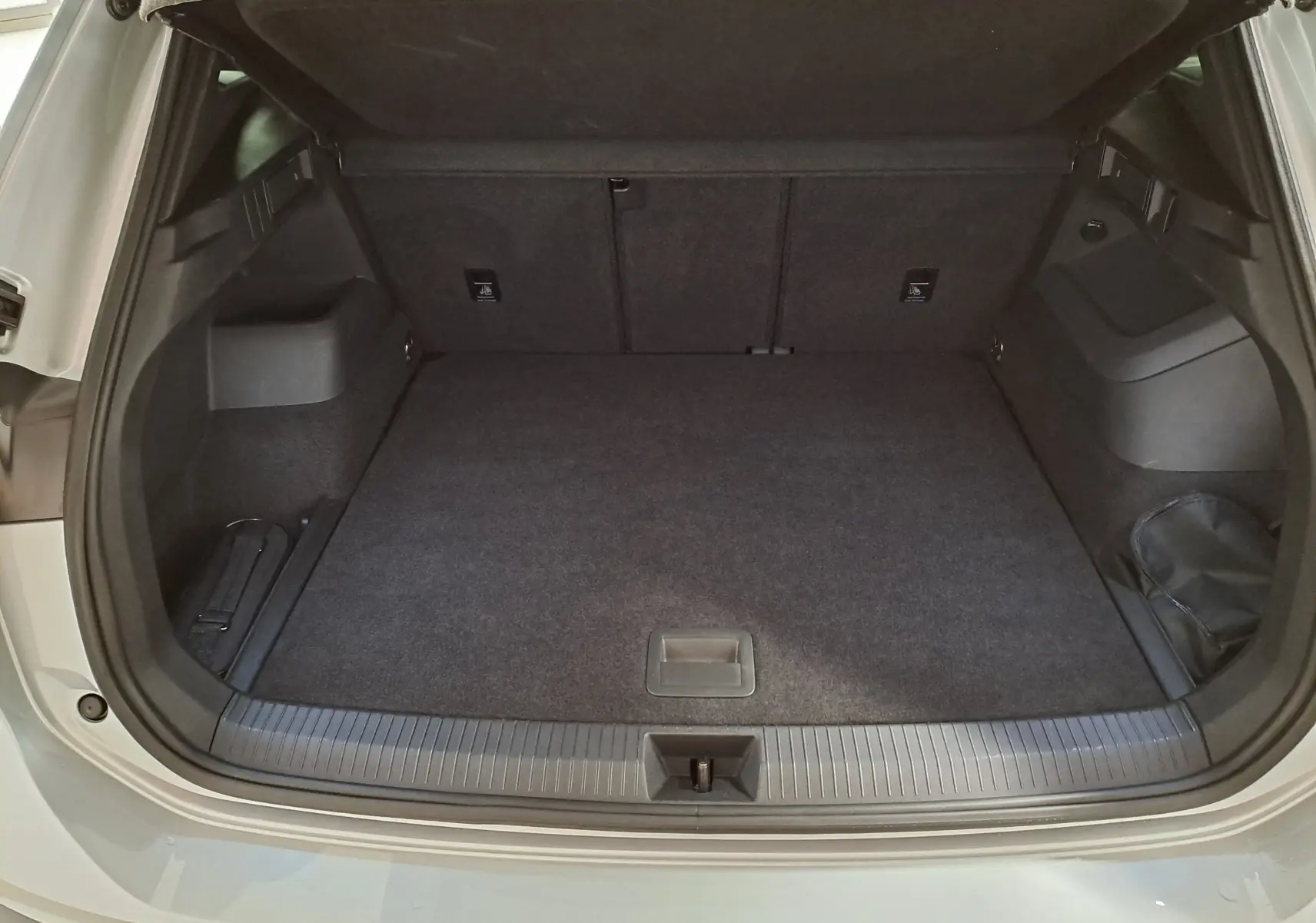 Coffre ouvert vu de l'arrière d'un Volkswagen Tiguan 2.0 TDI 150 DSG7 R-Line argent Dolomite, intérieur noir.