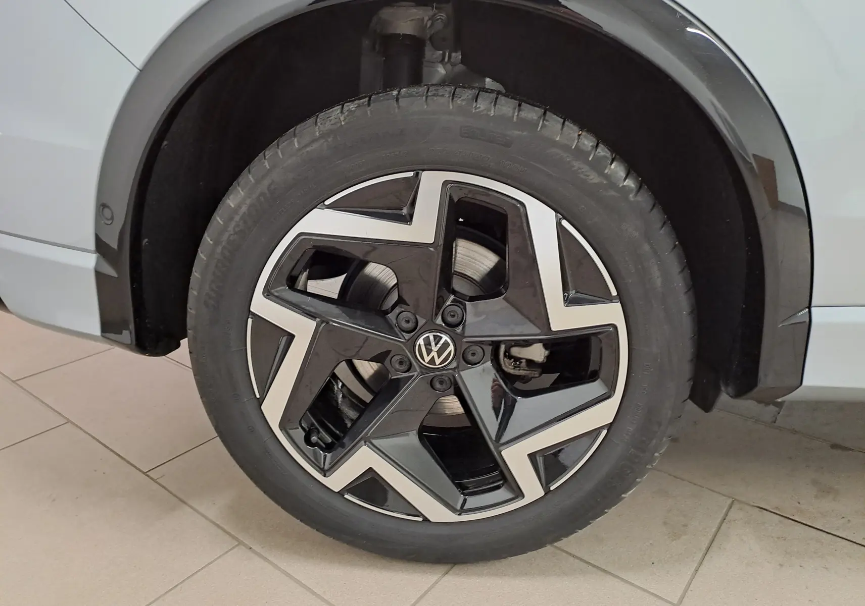 Gros plan sur la roue avant droite du Volkswagen Tiguan 2.0 TDI 150 DSG7 R-LINE argent Dolomite avec jante noire et argentée.