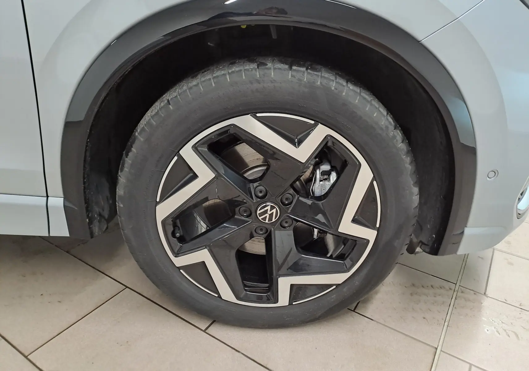 Gros plan sur la roue avant droite du Volkswagen Tiguan 2025 argent Dolomite avec jante R-Line noire et argentée au design géométrique.