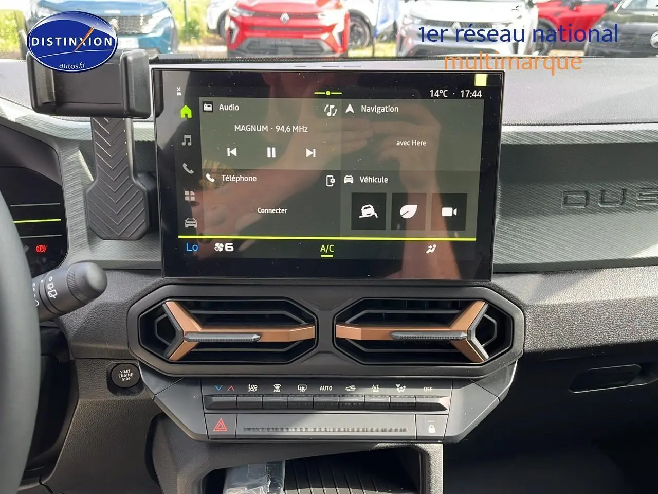 Vue intérieure du tableau de bord du Dacia Duster 2025 avec écran tactile et aérateurs hexagonaux couleur cuivre.