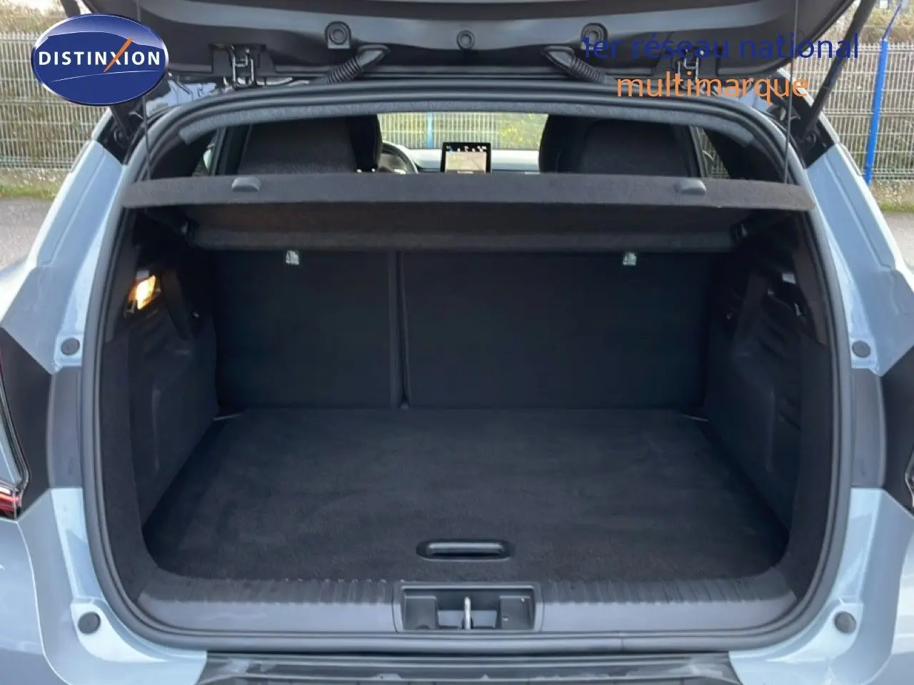 Coffre ouvert vu de l'arrière d'un Renault Captur gris Rafale métal avec toit noir, intérieur de coffre noir.