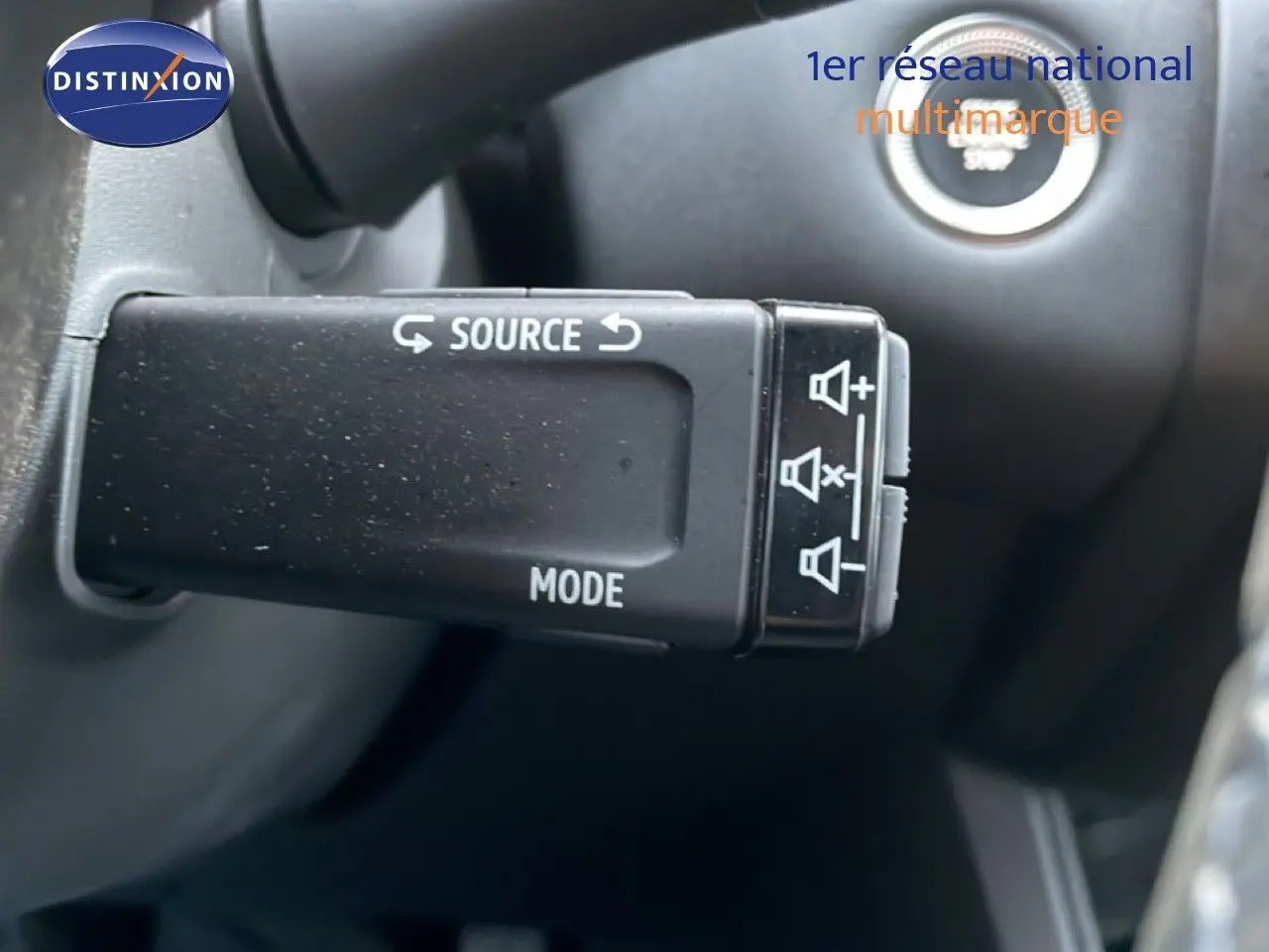 Gros plan sur la commande au volant Renault Captur 2025, bouton source et mode, intérieur noir.