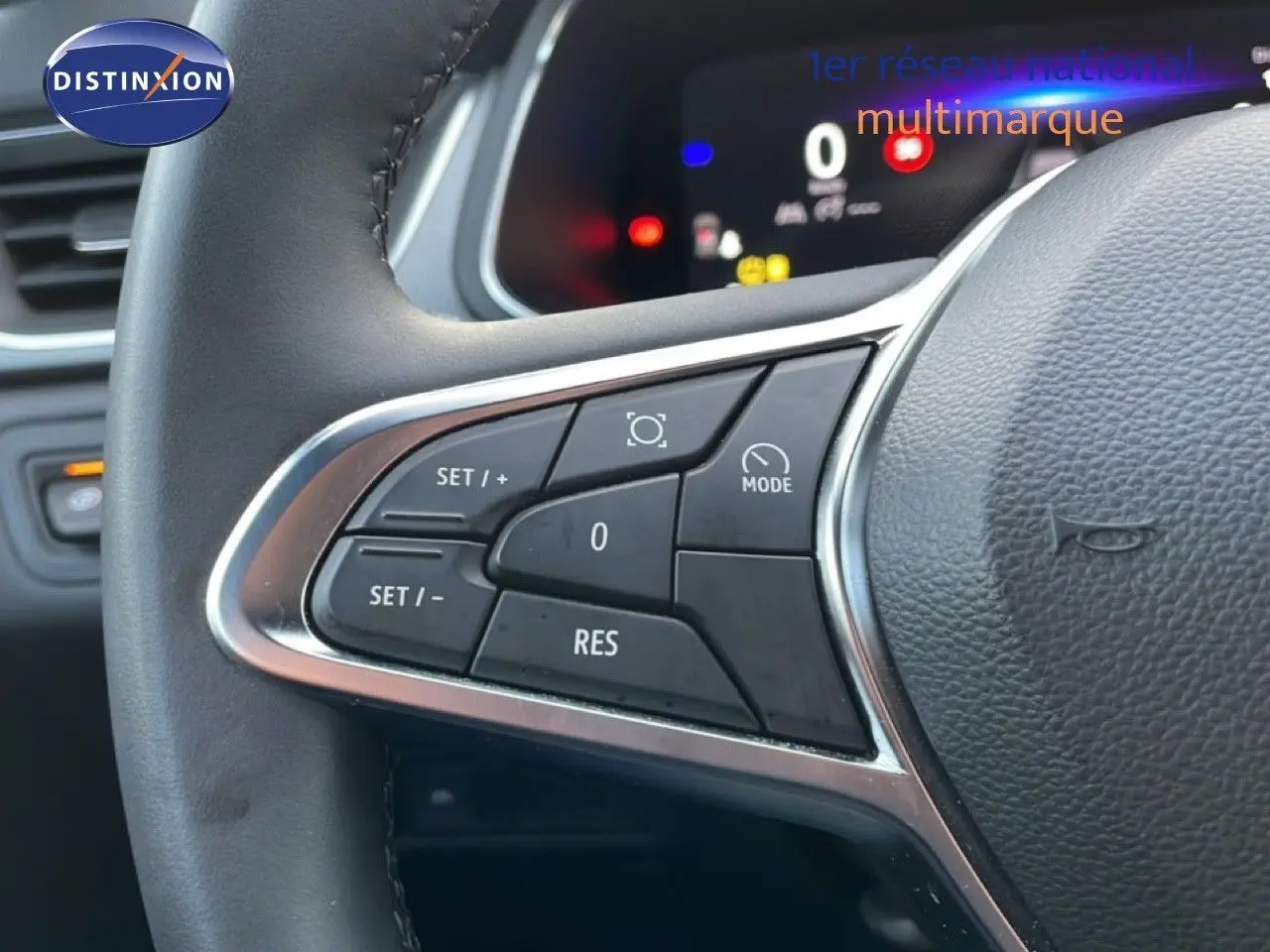 Gros plan sur les commandes au volant noir du Renault Captur 2025, affichage digital en arrière-plan flou.