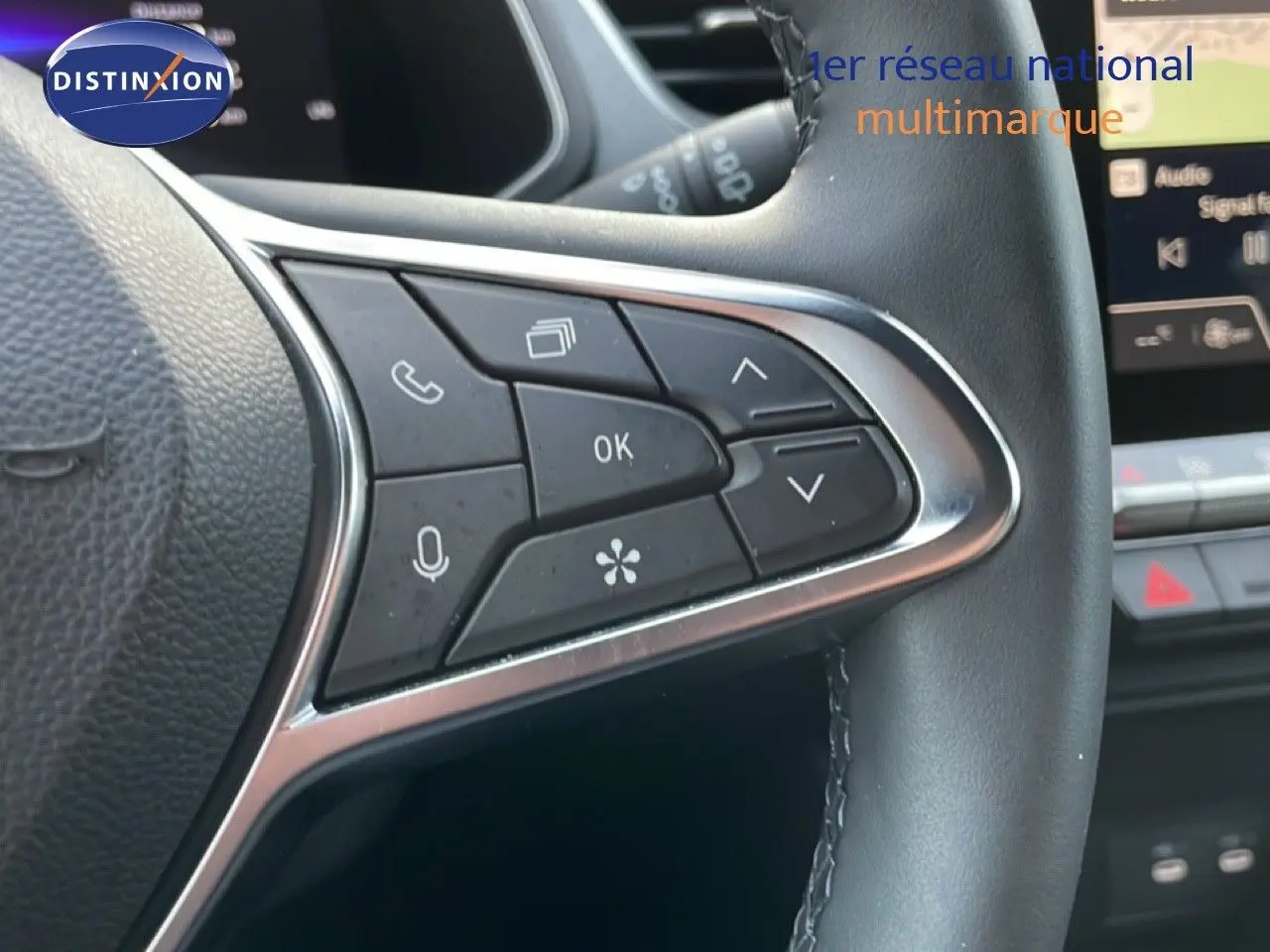 Gros plan sur les commandes multifonctions à gauche du volant cuir noir du Renault Captur gris Rafale métal 2025.