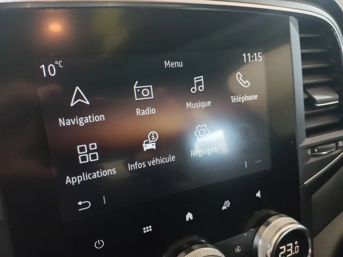 Écran tactile central de la Renault Mégane Business gris foncé, affichant menu navigation, radio et réglages.