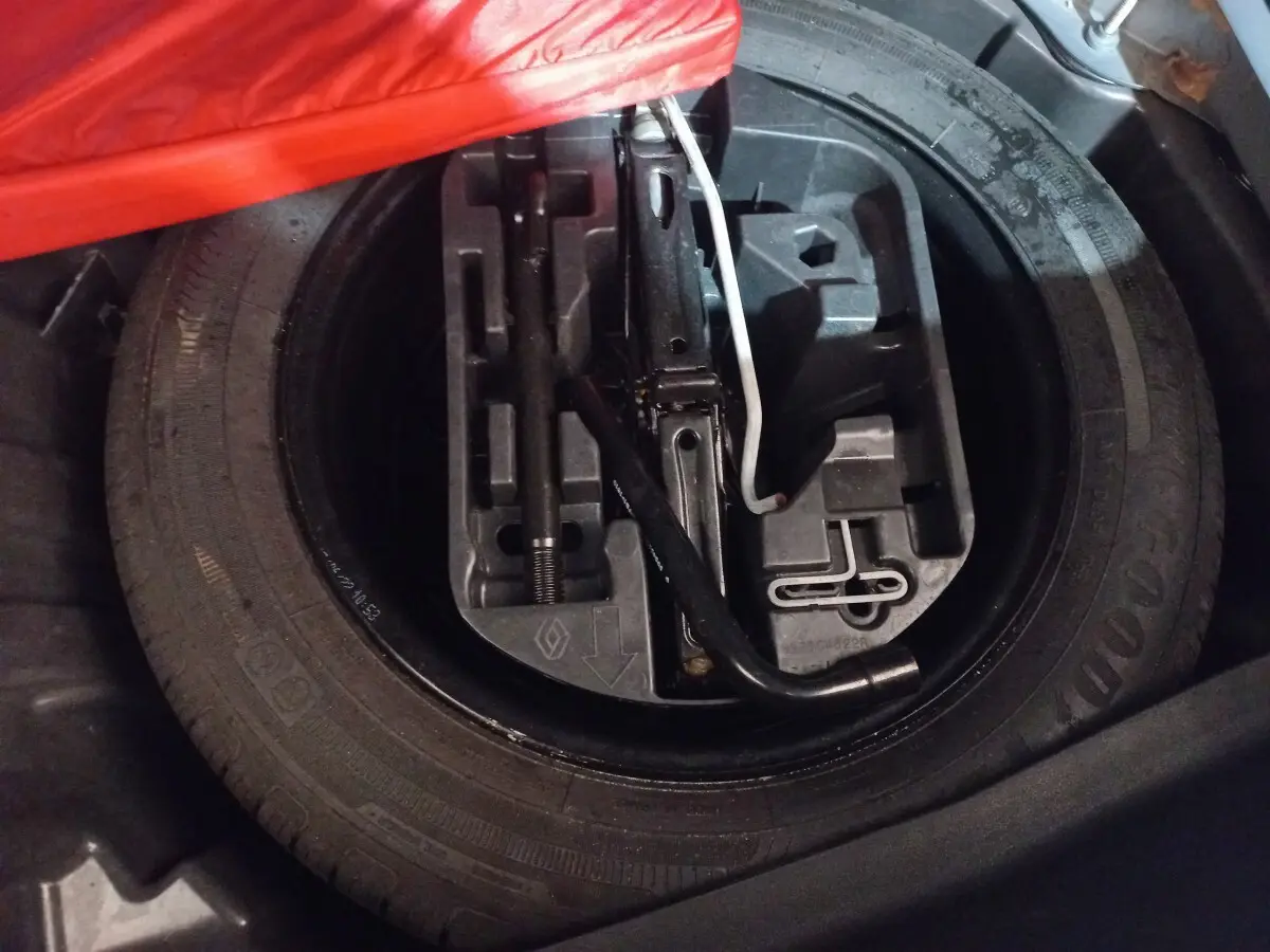 Vue rapprochée du coffre montrant la roue de secours et les outils de changement sur une Renault Mégane gris foncé.