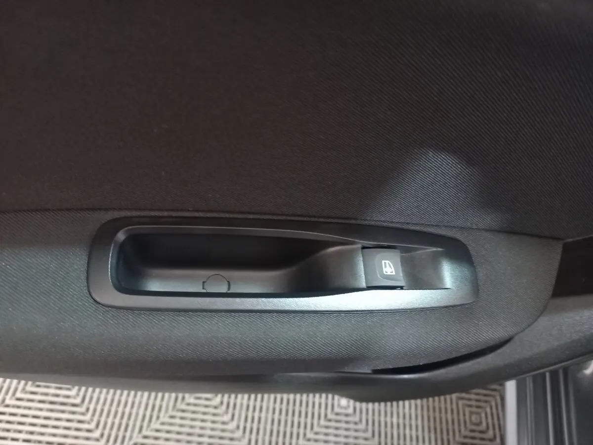 Gros plan sur la commande de lève-vitre côté droit de la porte intérieure d'une Renault Mégane Business gris foncé.