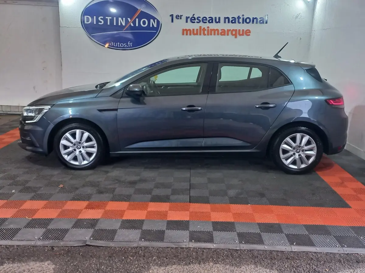 Renault Mégane Business TCe 115 gris foncé vue de profil côté gauche, en intérieur sur sol damier noir et orange.