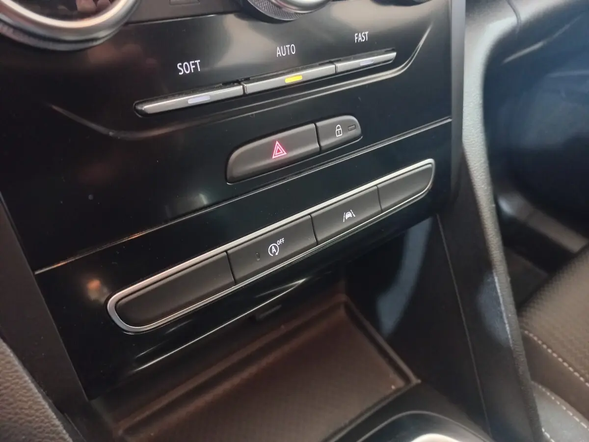 Gros plan sur la console centrale noire de la Renault Mégane Business TCe 115, montrant les boutons de sécurité et climatisation.