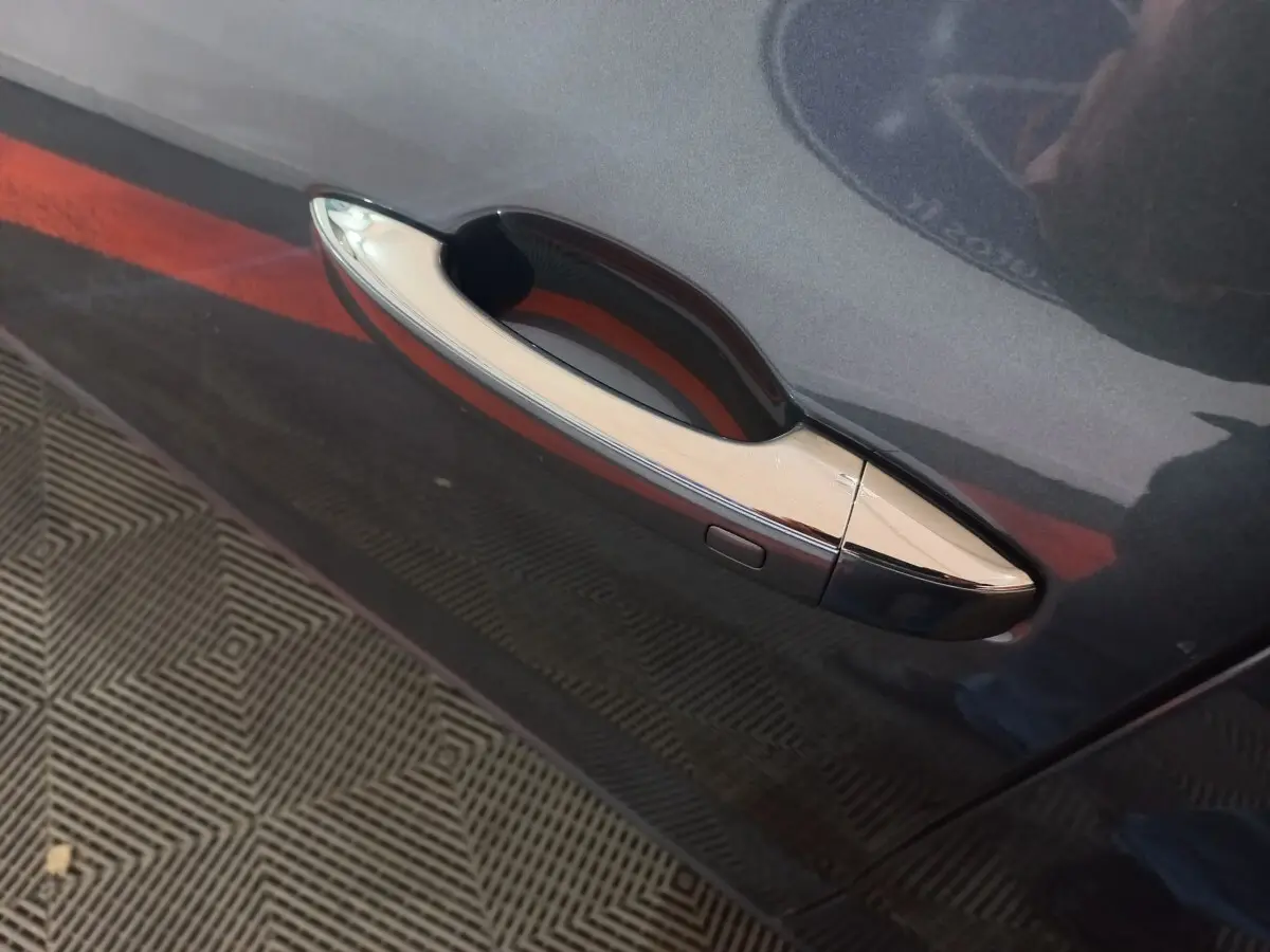 Poignée de porte chromée sur la portière côté gauche d'une Renault Mégane Business gris foncé vue en gros plan.