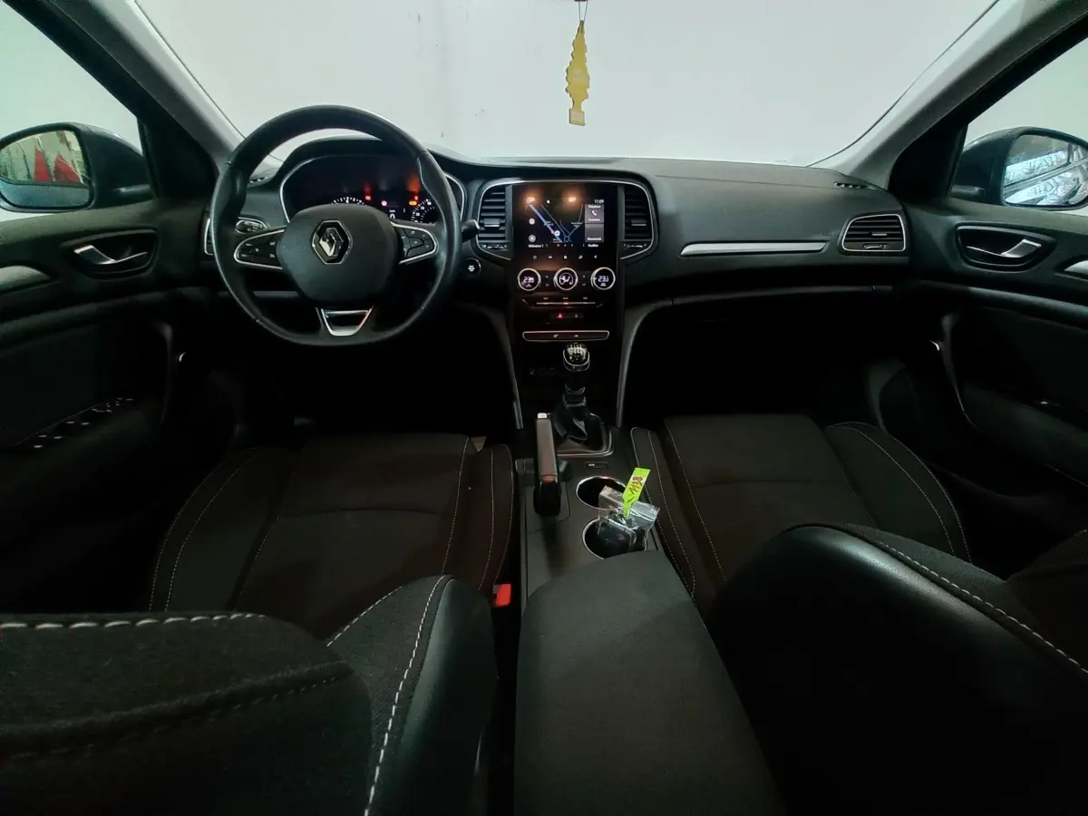 Vue intérieure avant de la Renault Mégane Business TCe 115, tableau de bord noir avec écran tactile central et volant multifonctions.