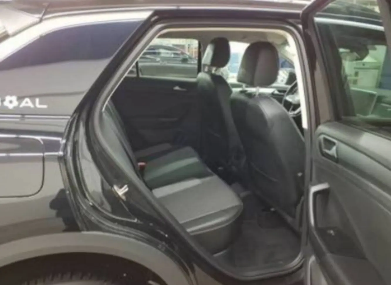 Vue intérieure côté gauche du Volkswagen T-Roc noir 2025, portes arrière ouvertes montrant les sièges arrière en tissu noir.