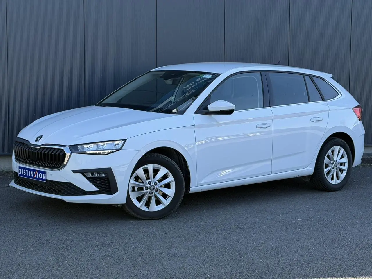 Vue 3/4 avant droite d'une Skoda Scala blanc glacier avec jantes alliage et vitres surteintées.