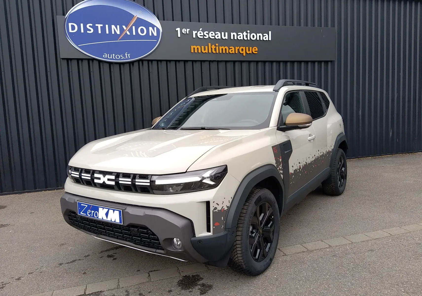 Dacia Duster Hybrid-G 150 ch en Sandstone, vue 3/4 avant droit avec décor pixelisé noir et rouge sur les flancs.