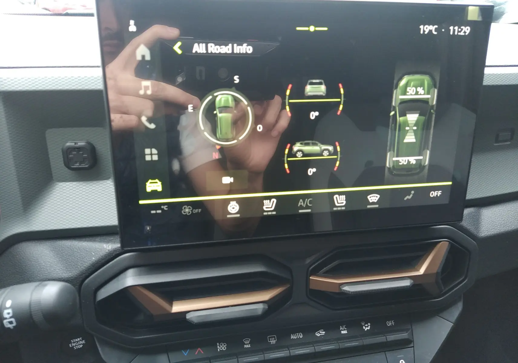 Écran tactile central du Dacia Duster Hybrid-G 150 ch, affichant les infos tout-terrain, avec aérateurs noirs et bronze en dessous.