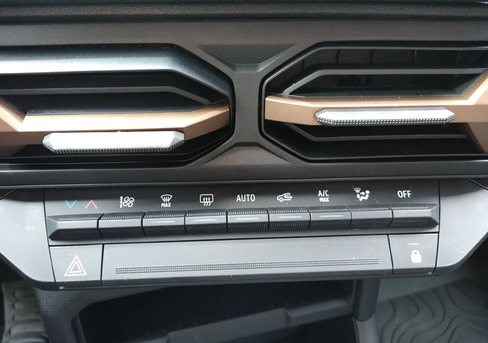 Détail de la console centrale du Dacia Duster 2026 avec commandes climatisation et aérateurs couleur sandstone.