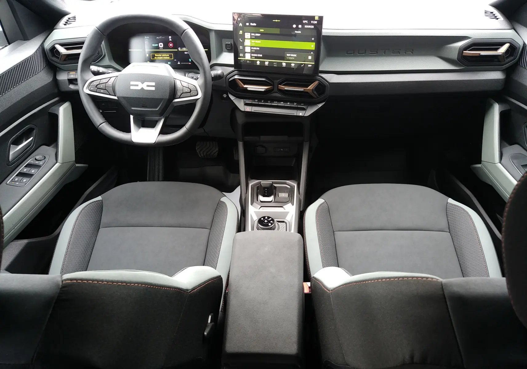 Vue intérieure avant du Dacia Duster Hybrid-G 150 ch 4x4 en finition Spirit of Sand, avec tableau de bord moderne et écran tactile central.