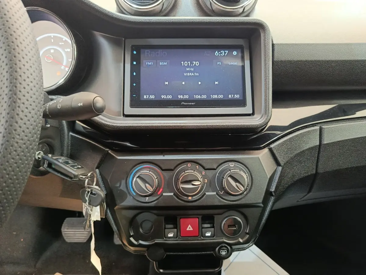 Vue intérieure centrée sur la console centrale et l’écran tactile d’une Aixam Ambition blanche, avec commandes de climatisation visibles.