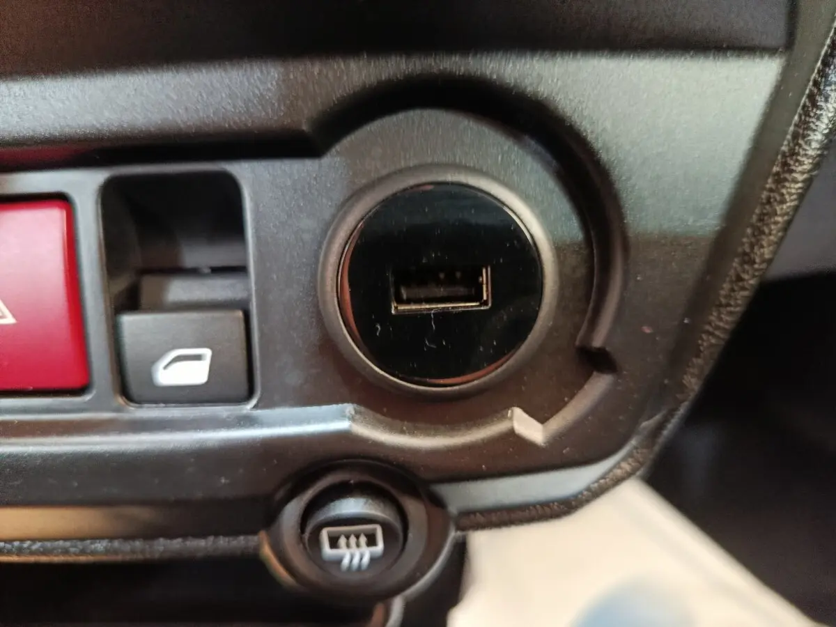 Gros plan sur la console centrale noire de l'AIXAM AMBITION 0.5 City Coupe Sport avec prise USB et boutons de commande.