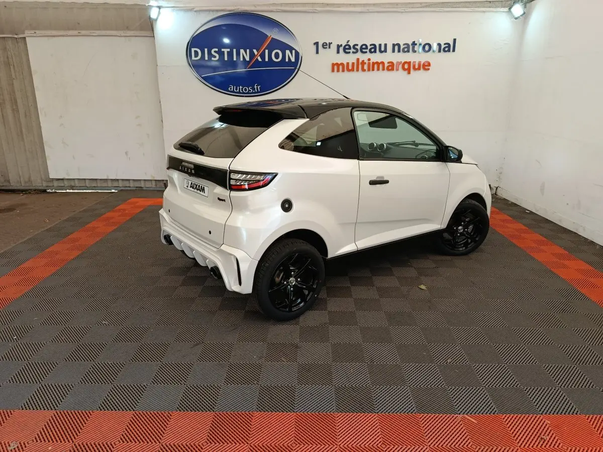 Vue 3/4 arrière droite d'une Aixam Ambition 0.5 City Coupe Sport blanche avec toit noir et jantes noires.