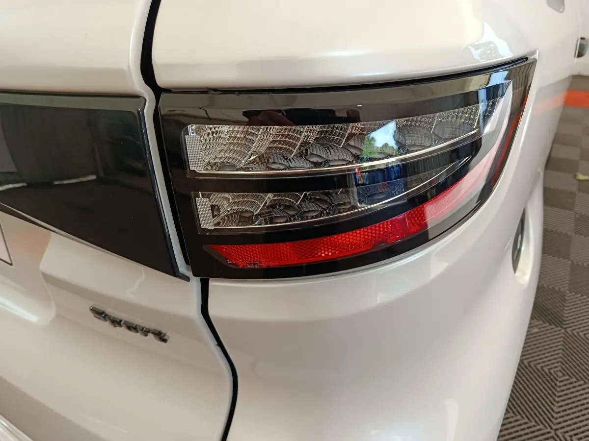 Gros plan sur le feu arrière droit blanc de l'AIXAM AMBITION 0.5 CITY COUPE SPORT 2026 avec détails noirs et rouge.