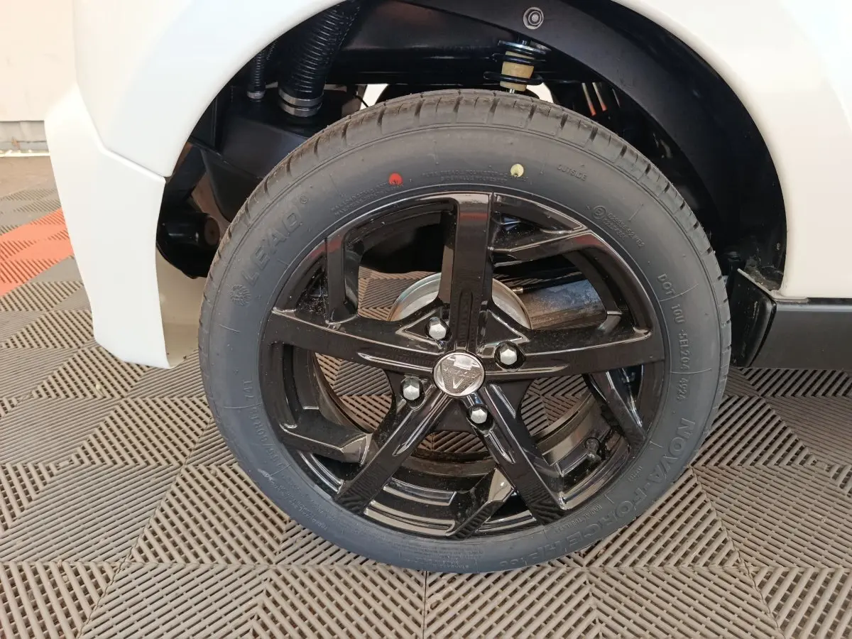 Gros plan sur la roue avant gauche avec jante noire brillante du véhicule blanc Aixam Ambition 0.5 City Coupe Sport 2026.