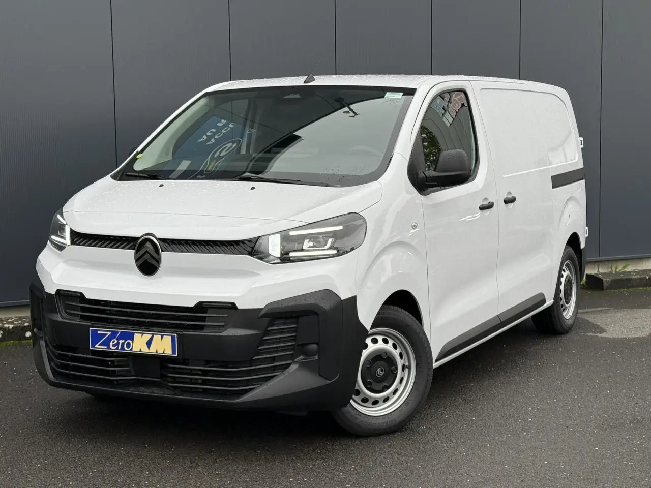 Vue 3/4 avant du Citroën Jumpy blanc Icy avec portes latérales et phares Full LED, stationné sur sol goudronné.