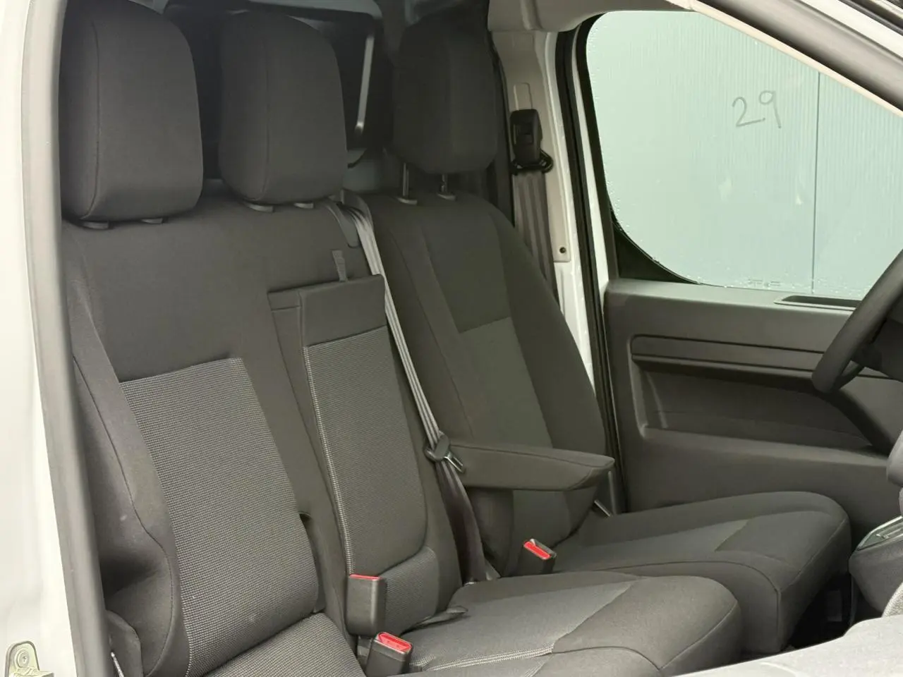 Vue intérieure côté conducteur du Citroën Jumpy blanc Icy, montrant la banquette 2 places avec siège latéral relevable.