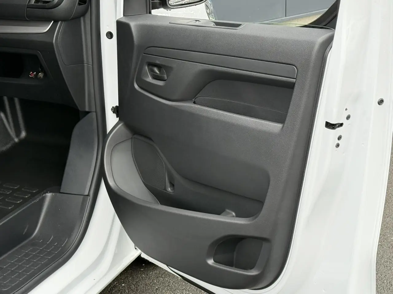 Vue rapprochée de la porte avant droite ouverte du Citroën Jumpy blanc Icy, montrant la garniture intérieure noire.