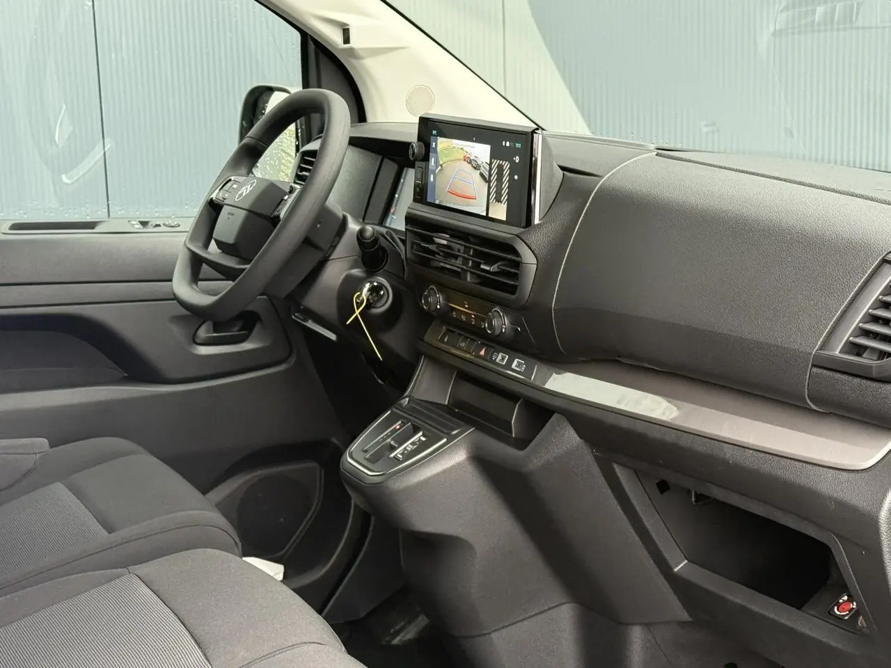 Vue intérieure côté conducteur du Citroën Jumpy blanc Icy, avec écran tactile affichant la caméra de recul et volant multifonction.