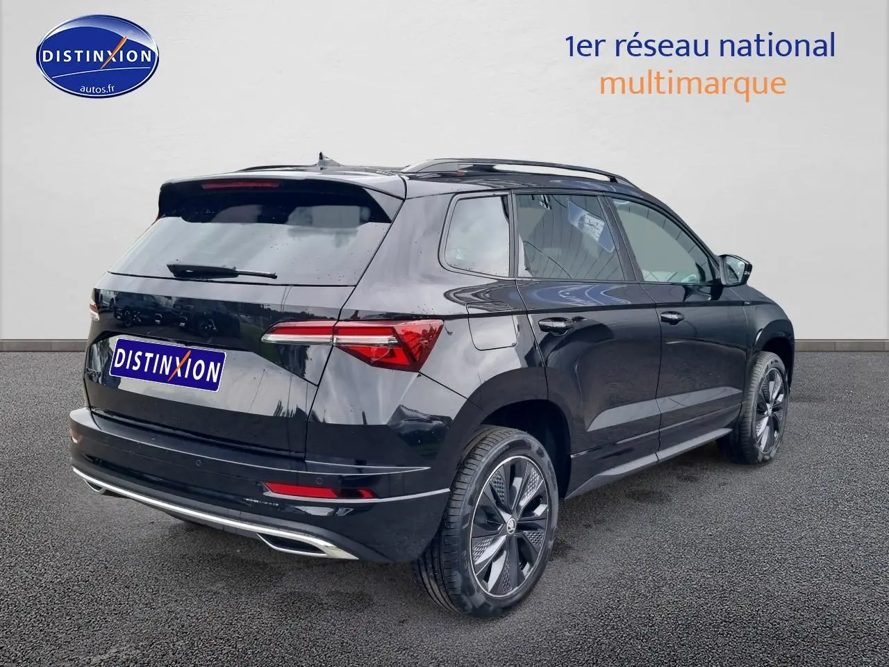 Vue 3/4 arrière droite d'un Skoda Karoq noir 2025 avec jantes alu et barres de toit visibles.