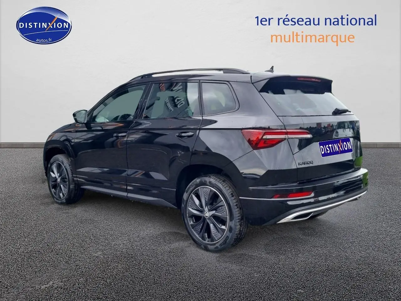 Vue 3/4 arrière droite d’un Skoda Karoq noir 2025 avec jantes alu et barres de toit visibles.