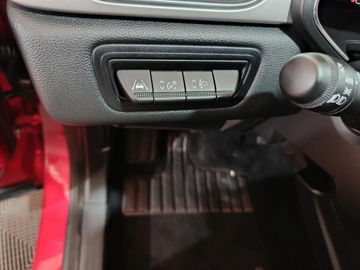 Vue intérieure côté conducteur du Renault Captur rouge 2024, boutons de réglage des aides à la conduite et éclairage.