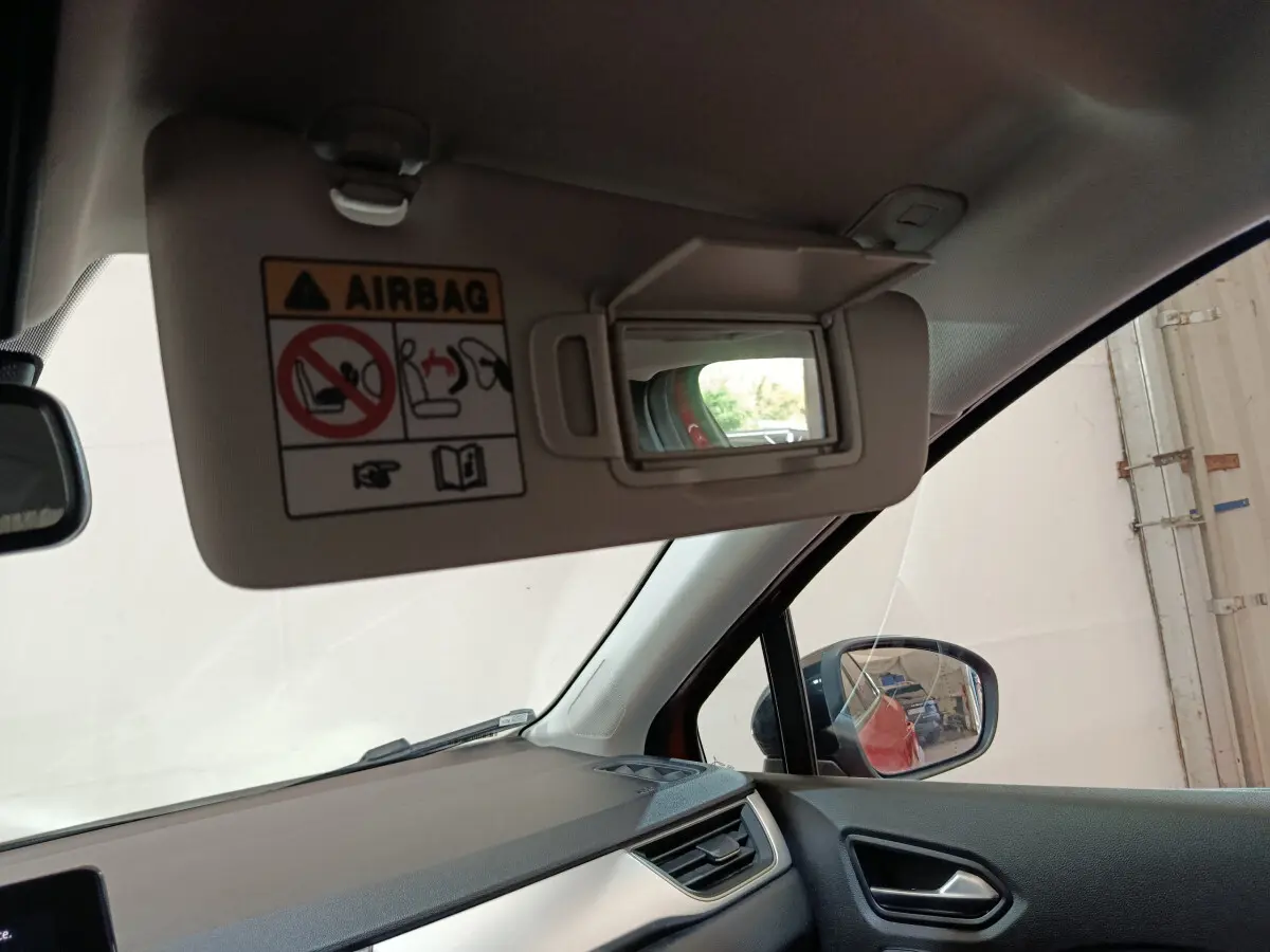 Vue intérieure côté conducteur du pare-soleil avec miroir et rétroviseur extérieur d’un Renault Captur rouge 2024.