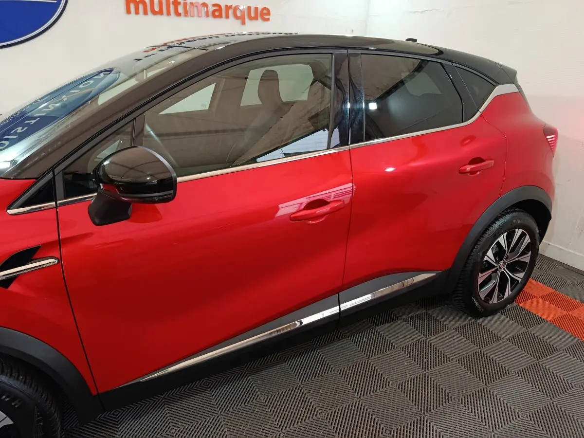 Vue latérale droite d'un Renault Captur rouge 2024 avec toit noir et jantes alliage distinctives.