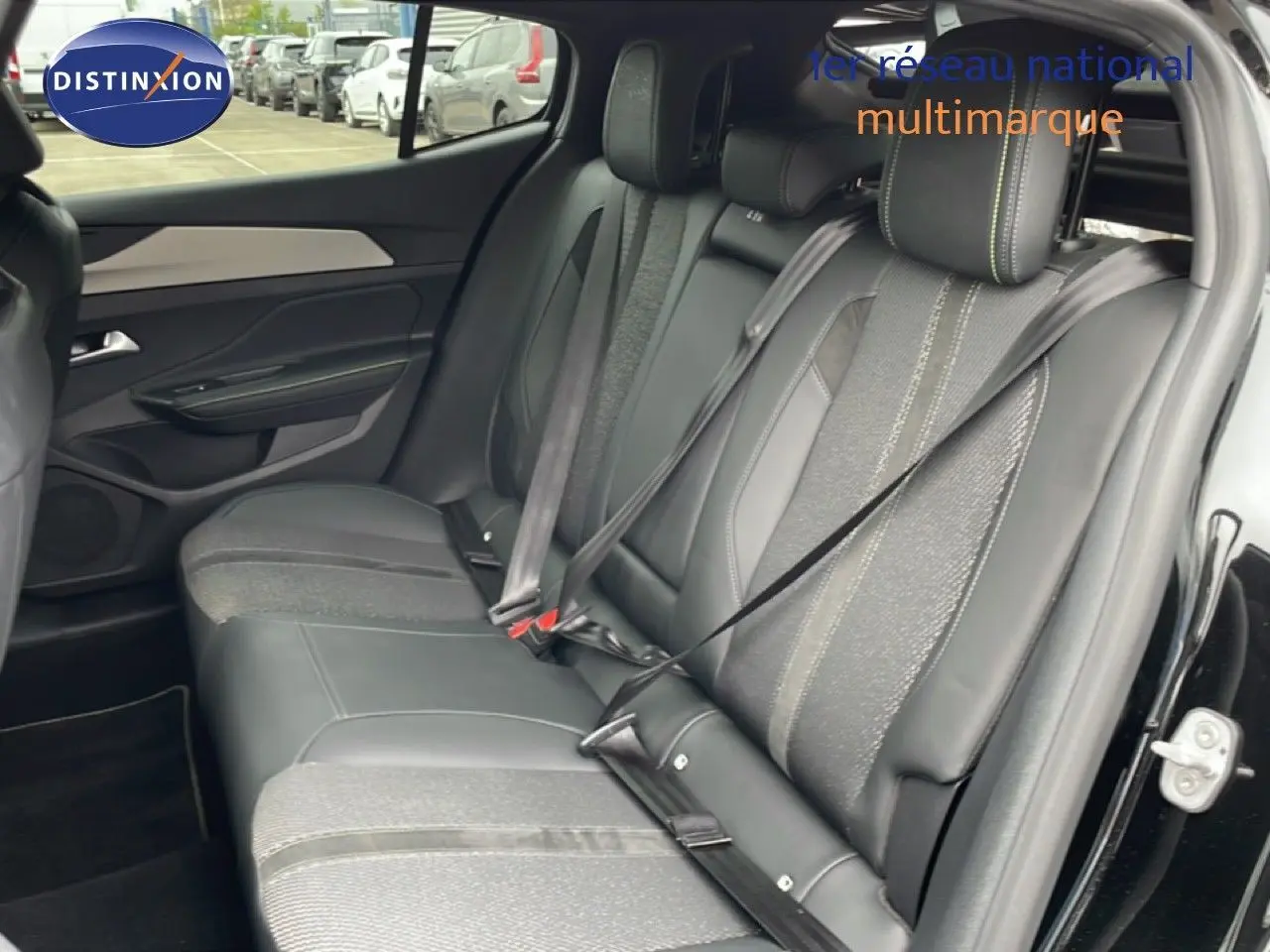 Vue latérale droite de l'intérieur arrière du Peugeot 408 noir métal, sièges mixtes cuir et tissu avec ceintures attachées.