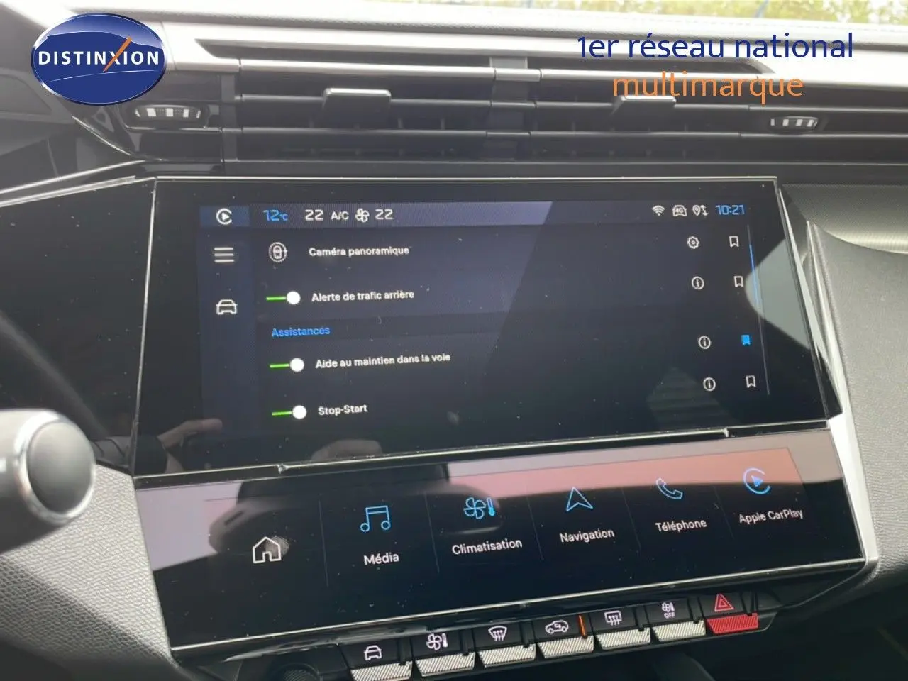 Vue rapprochée de l’écran tactile central noir du tableau de bord du Peugeot 408 1.2 Hybrid 2025, affichant les assistances et la climatisation.