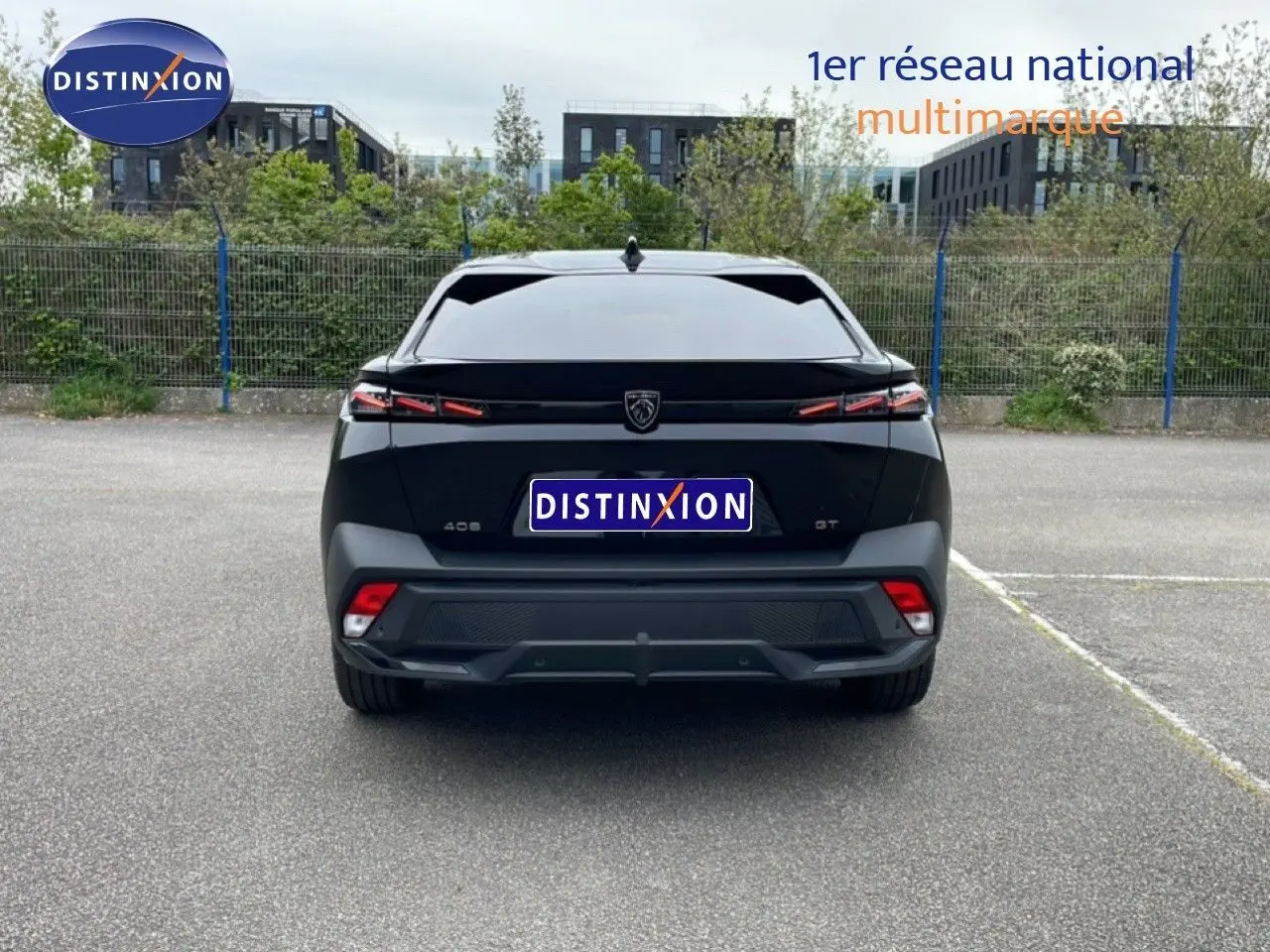 Vue arrière d'une Peugeot 408 GT noire métal 2025 avec feux LED distinctifs et logo central sur un parking.