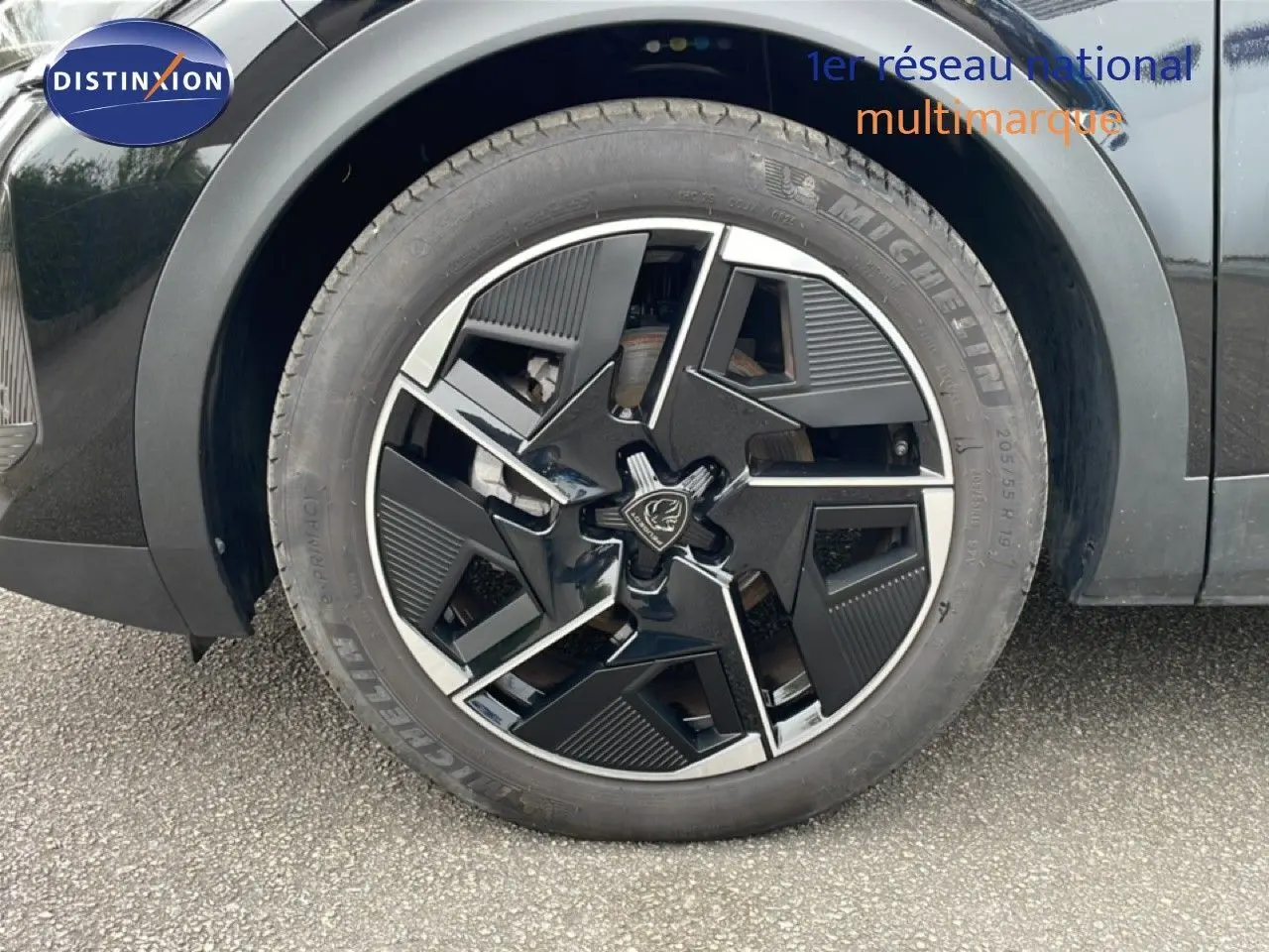 Gros plan sur la roue avant droite noire métal d'une Peugeot 408 1.2 Hybrid 145ch GT avec jante au design moderne.