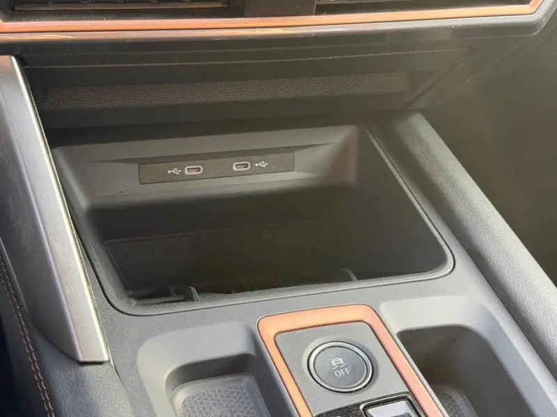 Gros plan sur la console centrale de la SEAT LEON 2025 avec ports USB-C et bouton de contrôle, finition noire et détails cuivrés.