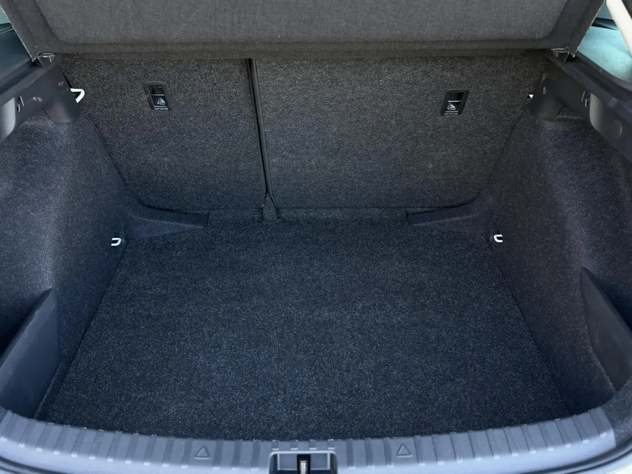 Coffre vide vu de face de la Skoda Scala TSI 116 blanc Glacier, avec revêtement intérieur gris foncé.