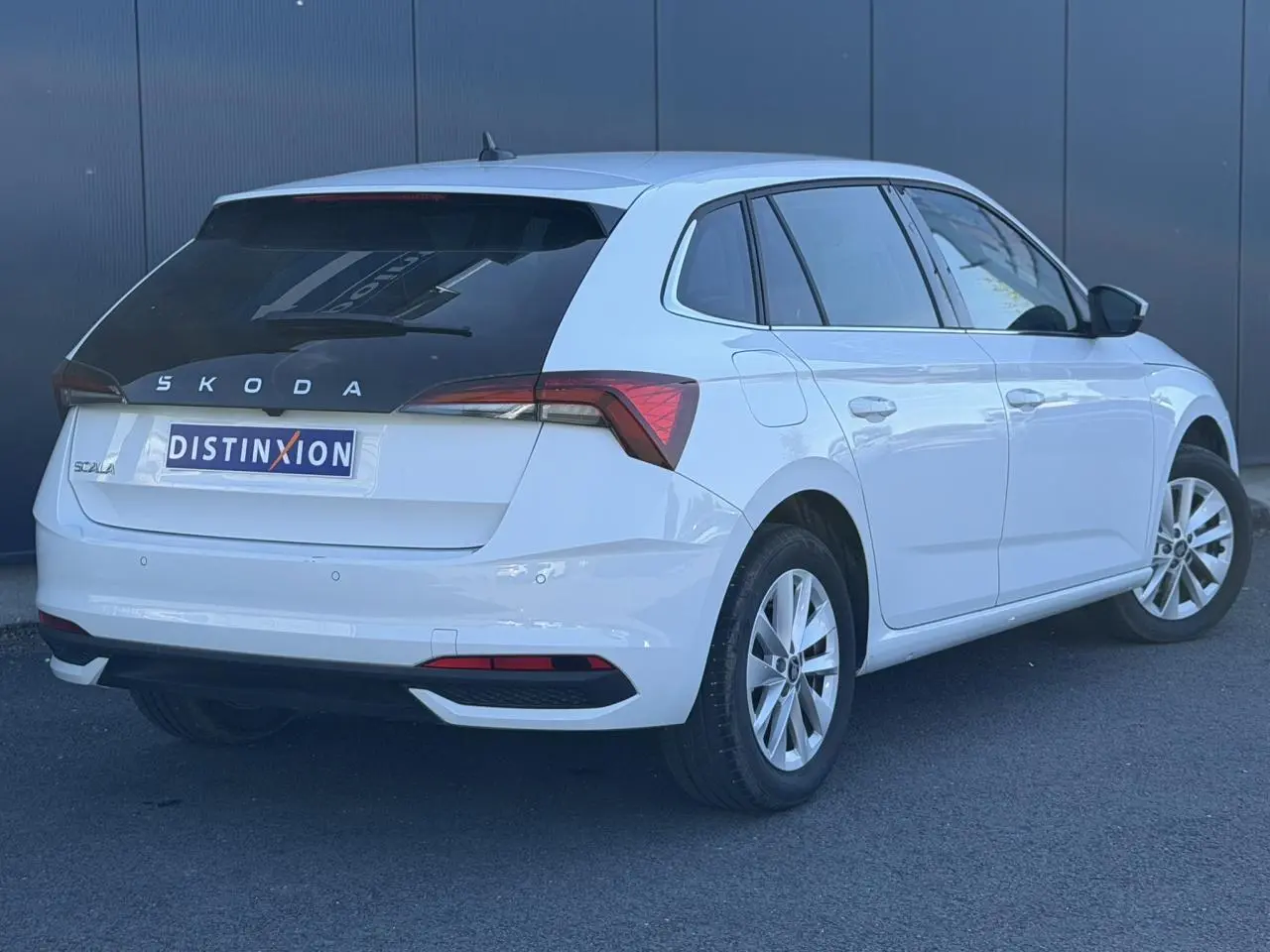 Vue 3/4 arrière droite d'une Skoda Scala blanc glacier avec vitres arrière surteintées et jantes alliage 16 pouces.